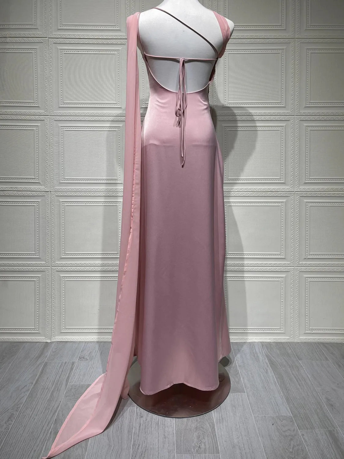 Pink evening gown on a mannequin against a gray paneled wall. #Color_Pink