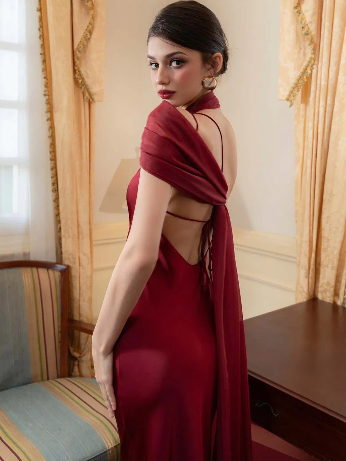 Woman in a red dress with a backless design in an elegant room. #Color_Red