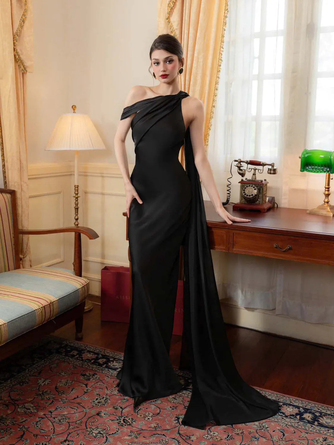 Woman in a black off-shoulder gown standing in an elegant room with classical decor. #Color_Black